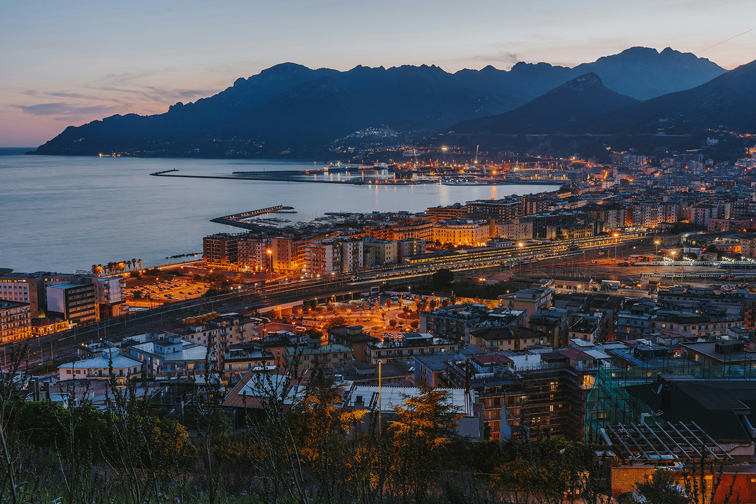 Salerno at dusk with the railway station, waterfront and ferry port overlooking the Gulf of Salerno.