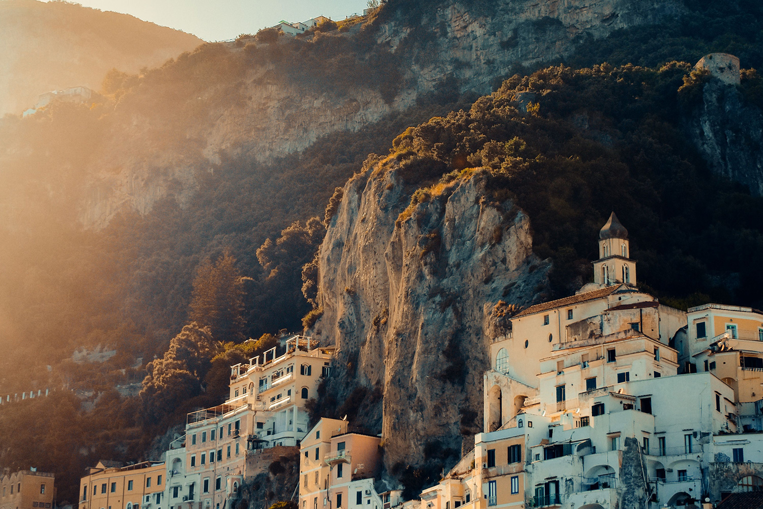 Amalfi Coast village in warm October golden-hour light beneath dramatic cliffs.