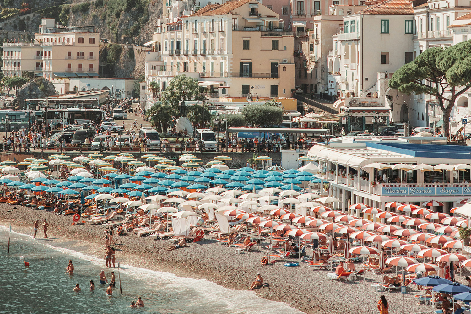 Minori Beach with colourful umbrellas and the historic town rising behind the waterfront on the Amalfi Coast