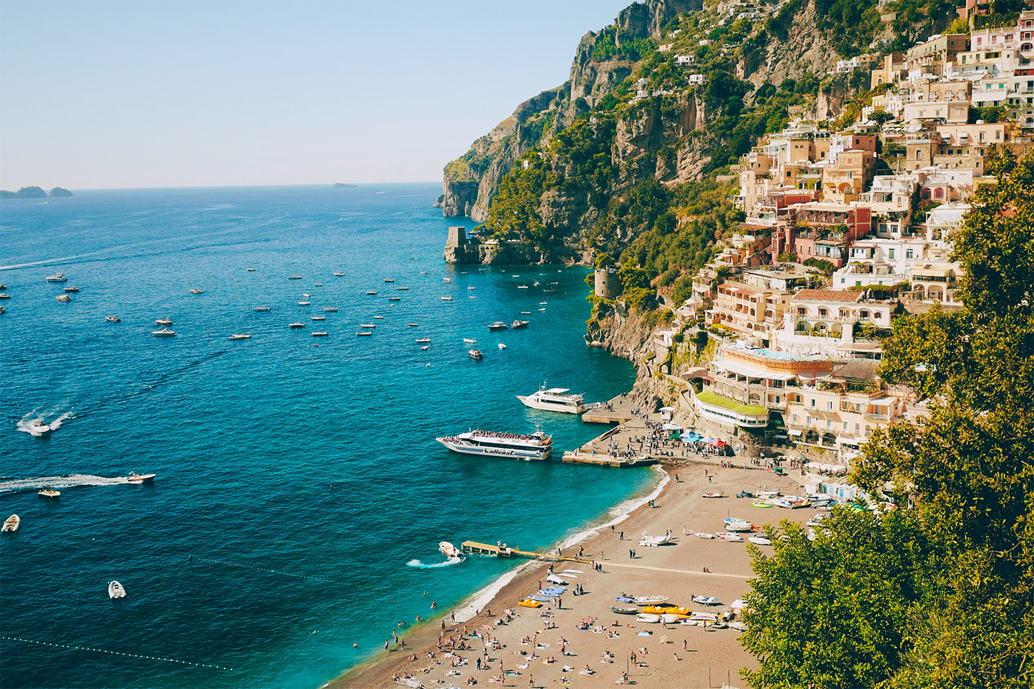 Spiaggia Grande beach in Positano with boats on the sea and colourful houses rising above the Amalfi Coast.