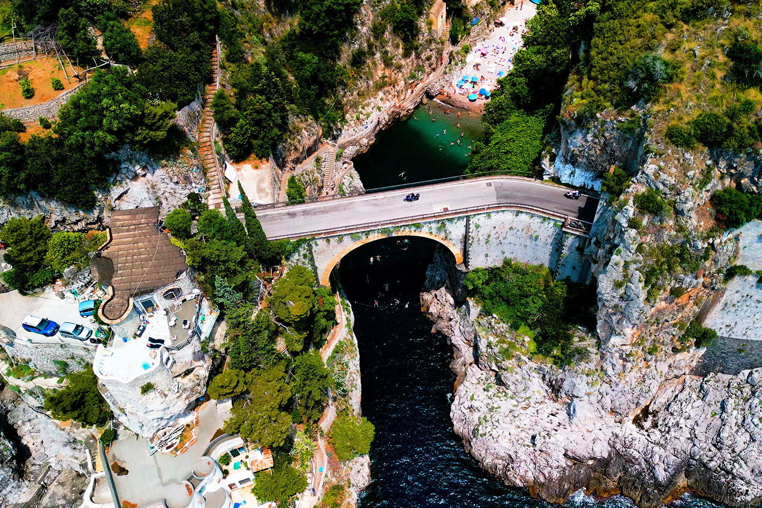 Aerial view of Fiordo di Furore showing the SS163 road crossing the gorge, the beach below and the steep surrounding cliffs.