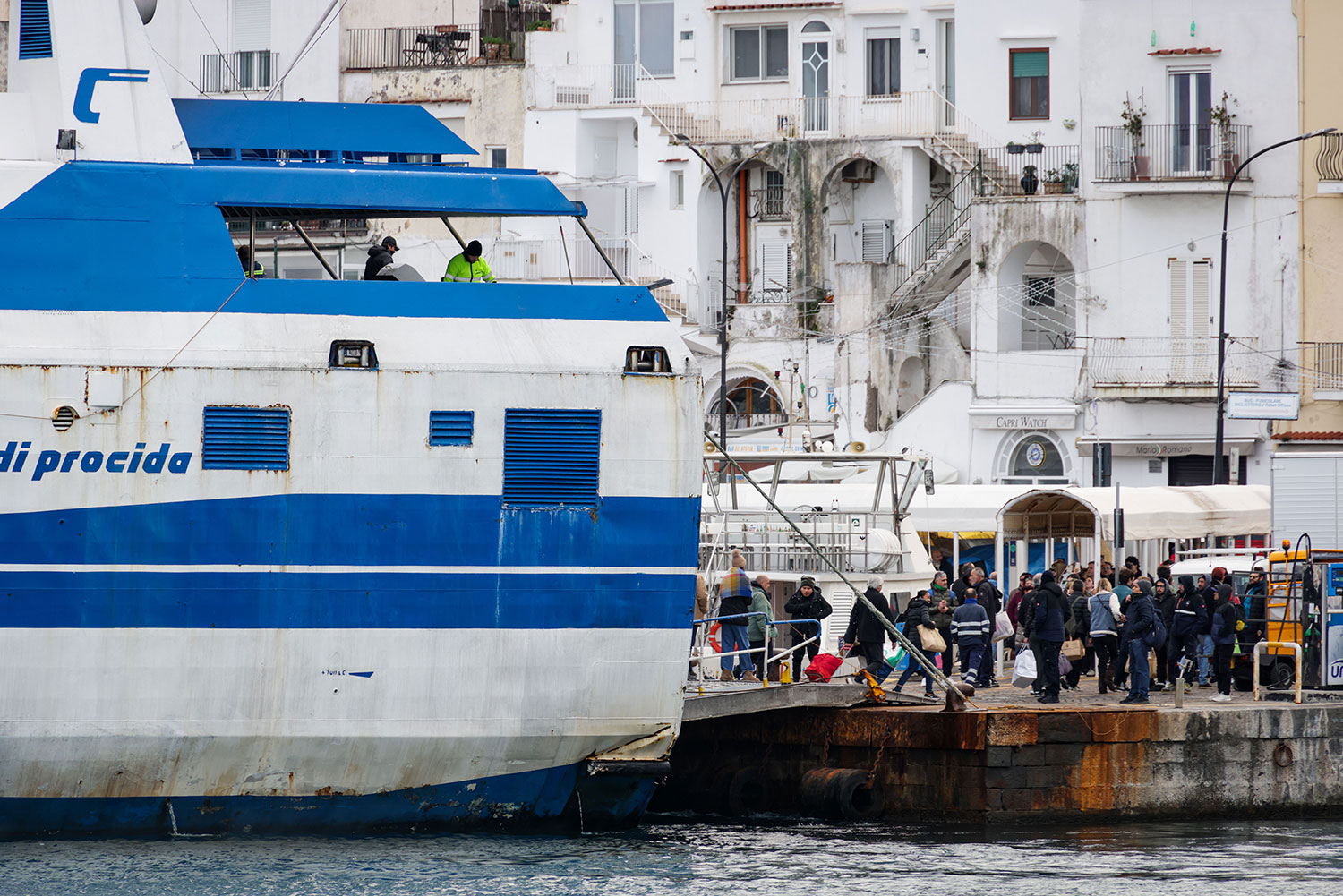 Passengers boarding a large coastal ferry at a busy harbour in Campania.