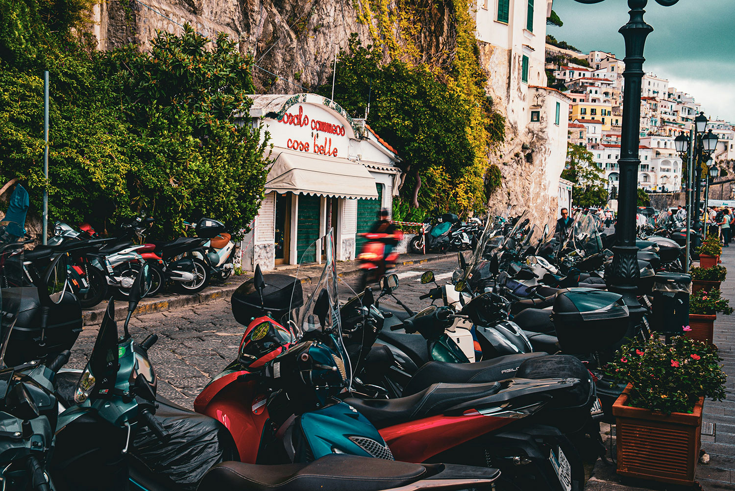 Scooters and motorcycles parked along a scenic street on the Amalfi Coast.
